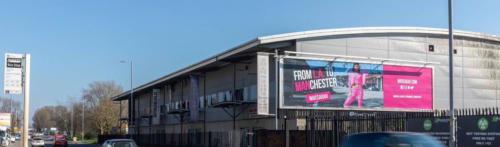 Clear Channel billboard on side of building on a busy road