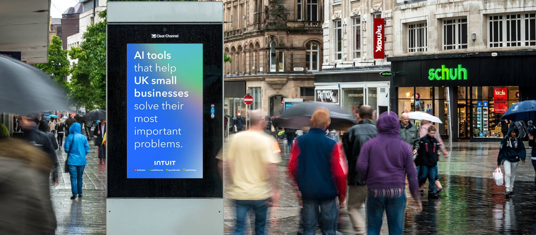 Clear Channel Adshel Live digital screen in the middle of a busy square on a rainy day