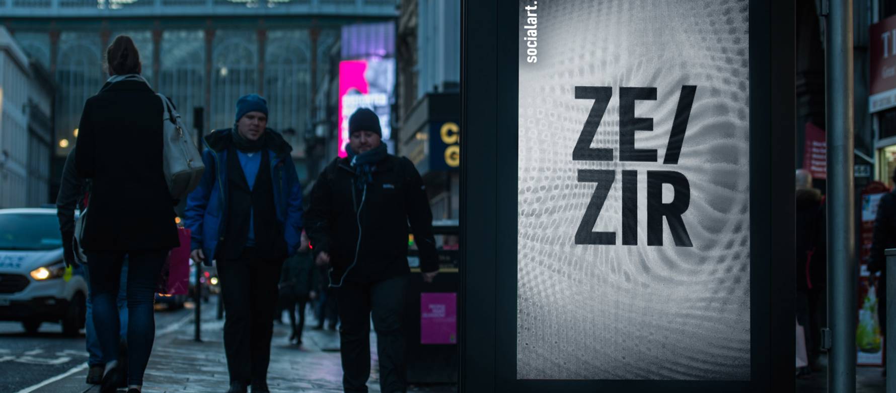 Ze/Zir pronouns displayed on a digital screen as pedestrians walk by at dusk