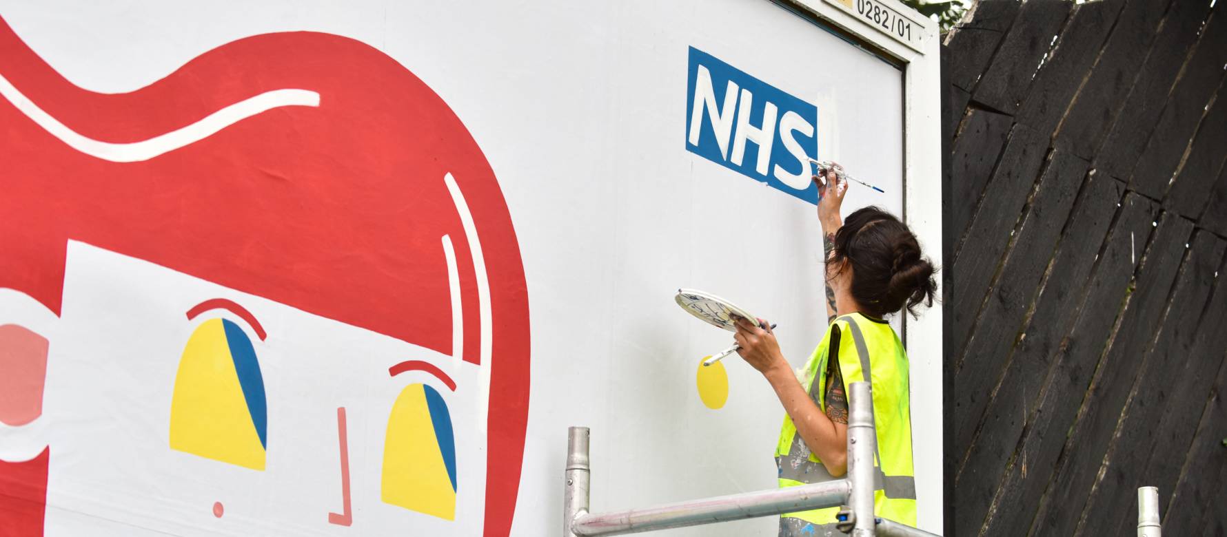 Painter painting a NHS logo on a billboard