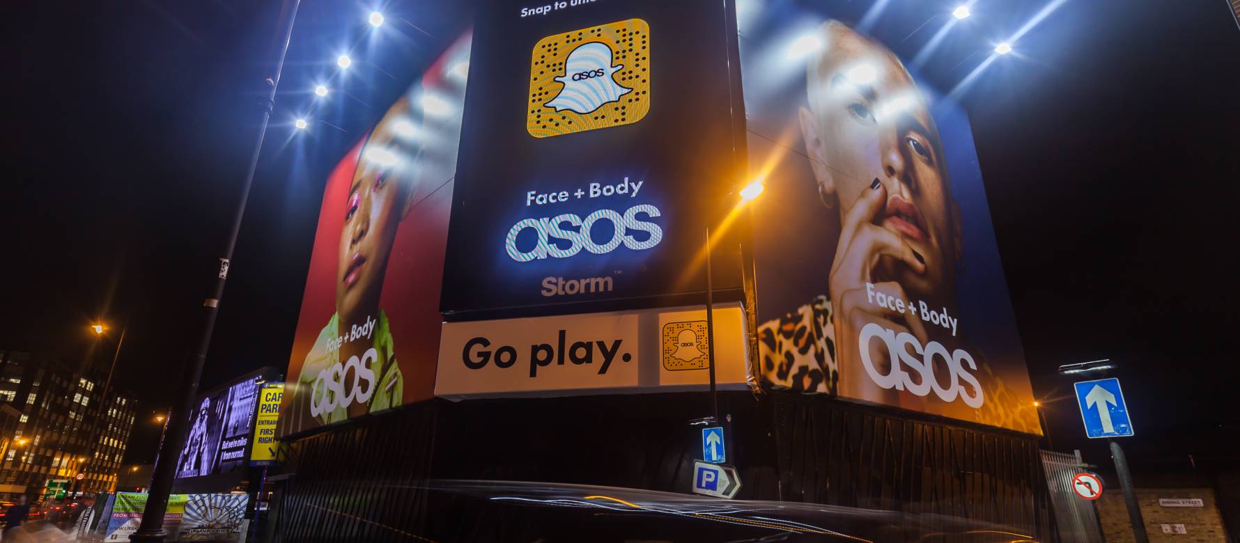 A Storm billboard with a Snapchat advertisement in the middle and two ASOS advertisements on either side displayed at Shoreditch Triangle