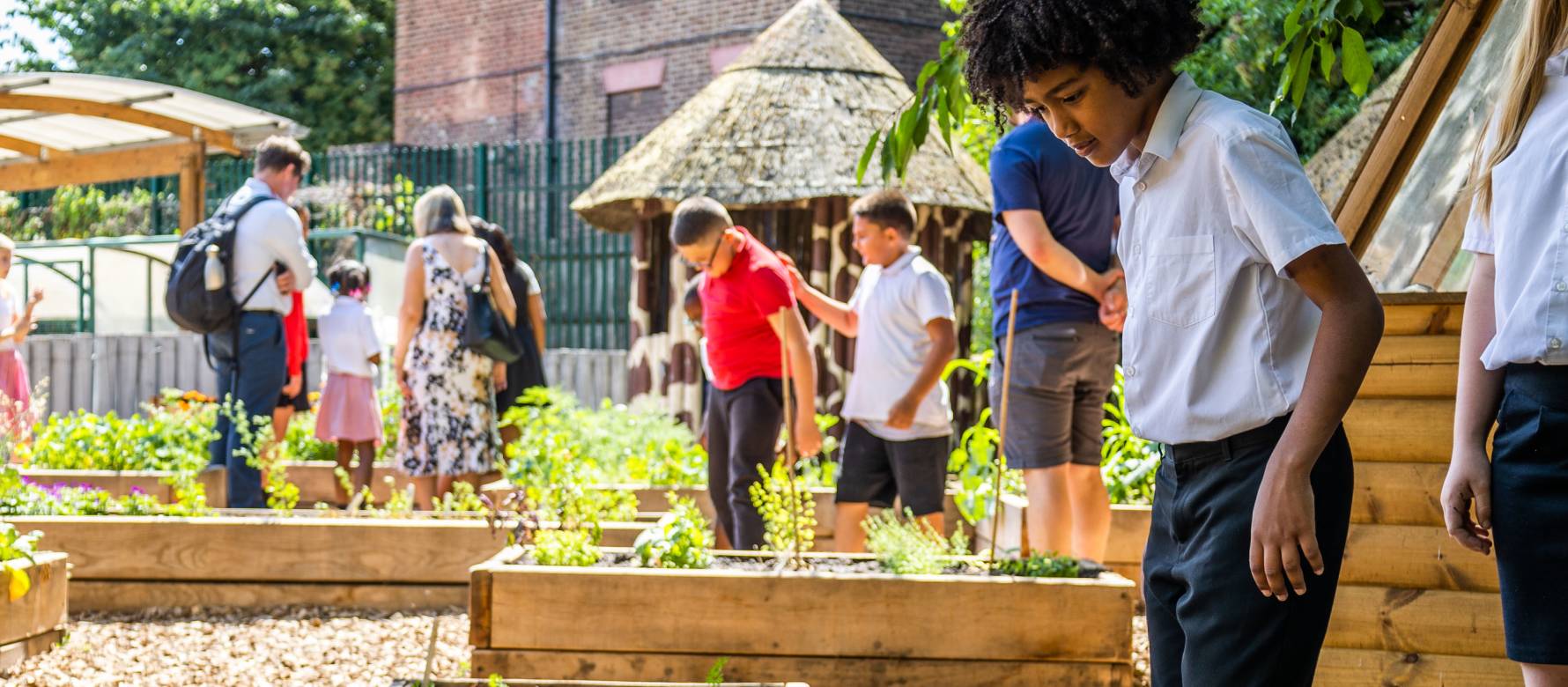 School Children looking in the plants in the flower beds of the edible playground