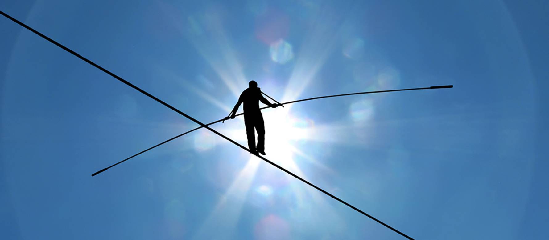 A shadow of a tightrope walker with a sunny sky in the background