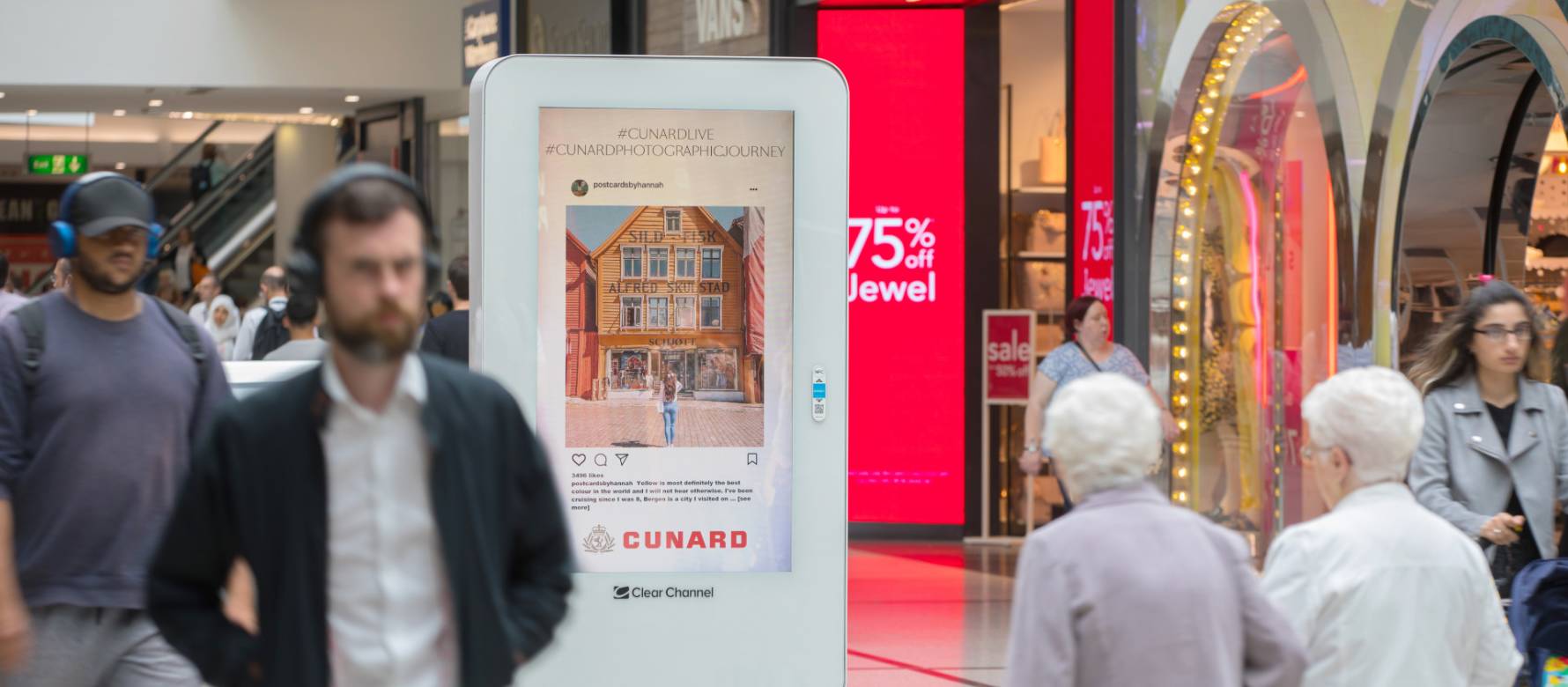 Digital screen in a busy shopping mall showing Cunard advert