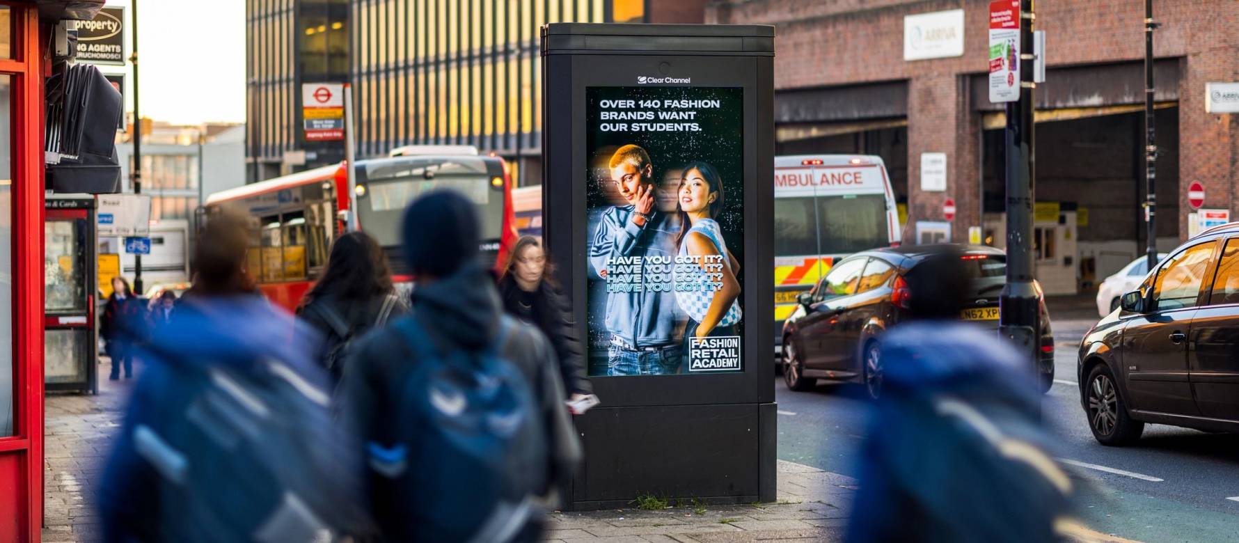 People walking past a fashion advert on Adshel Live next to traffic