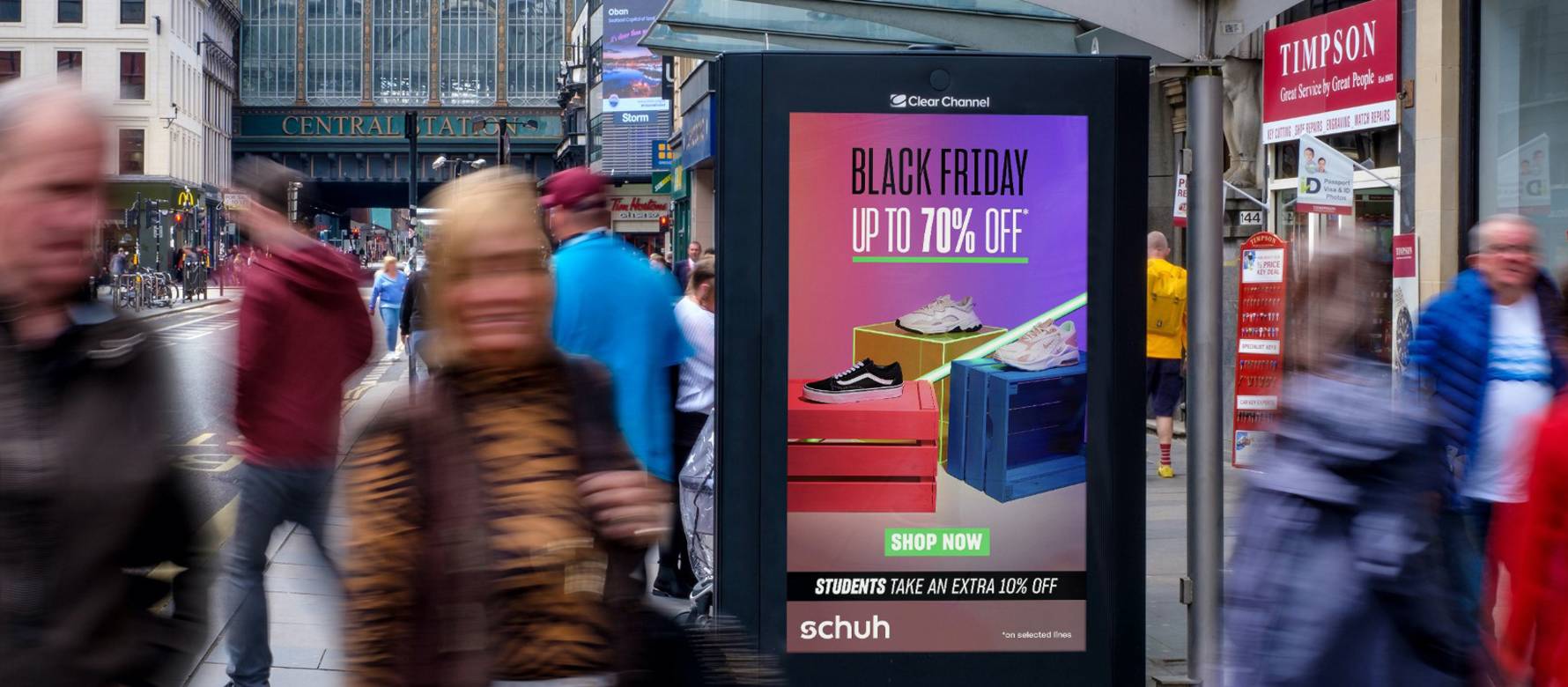 Schuh Black Friday advertisement on Adshel Live at a bus shelter on a busy road