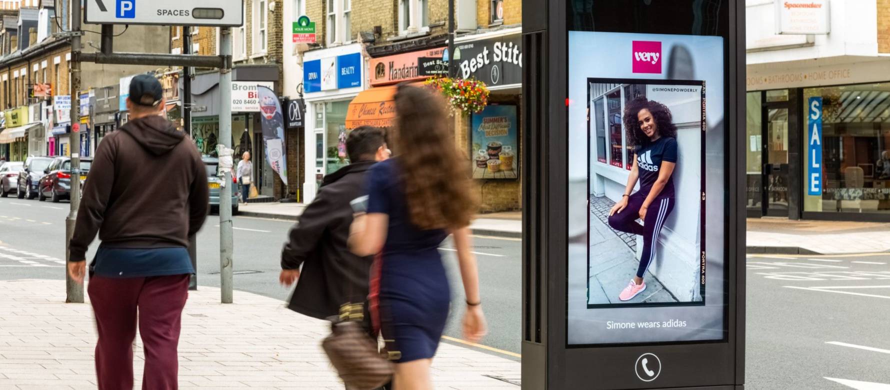 Adshel screen displays 'very' fashion, people walking by