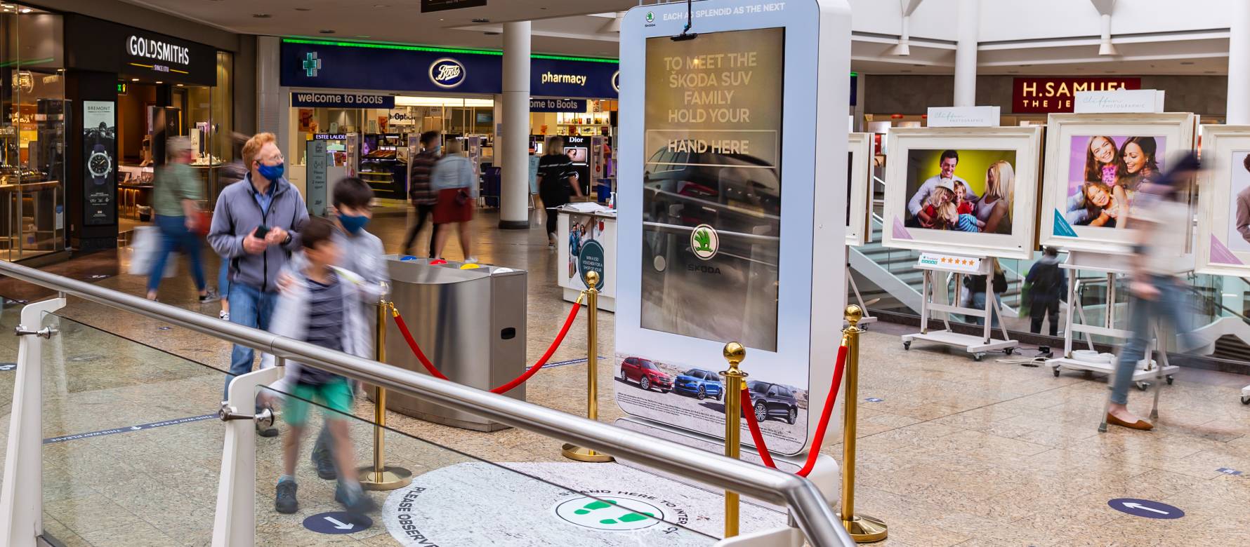 Digital screen in a busy shopping mall near Boots & H Samuel showing Skoda advert