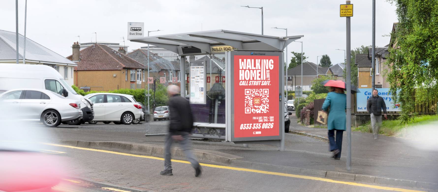 Strut Safe advertising on a Clear Channel bus shelter as pedestrians walk by during the day