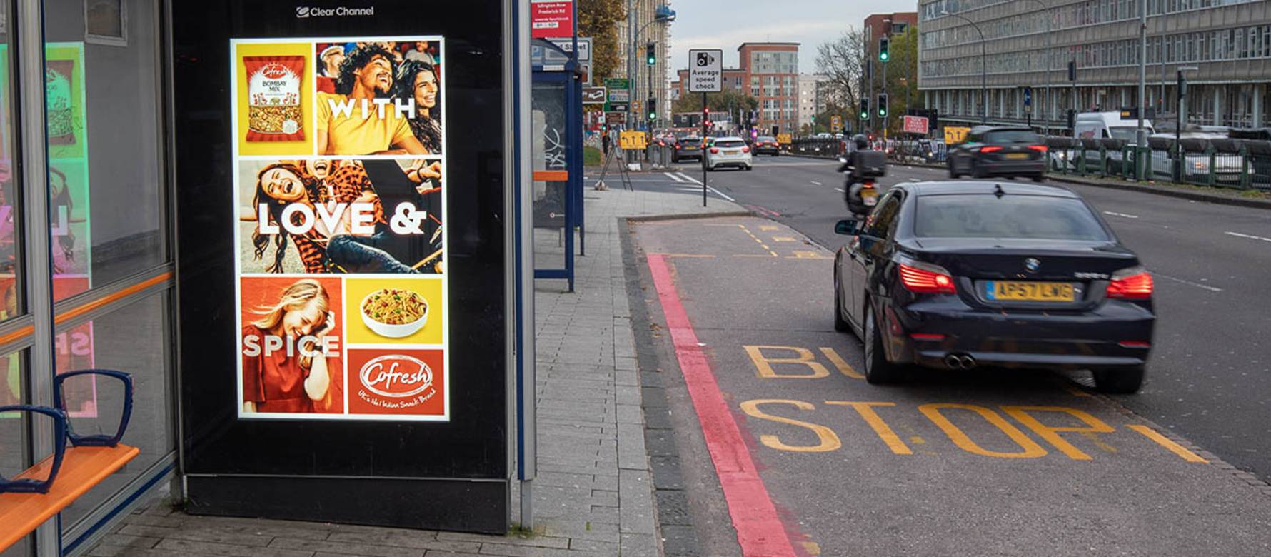 An FMCG digital screen advert with motorbike and cars driving past