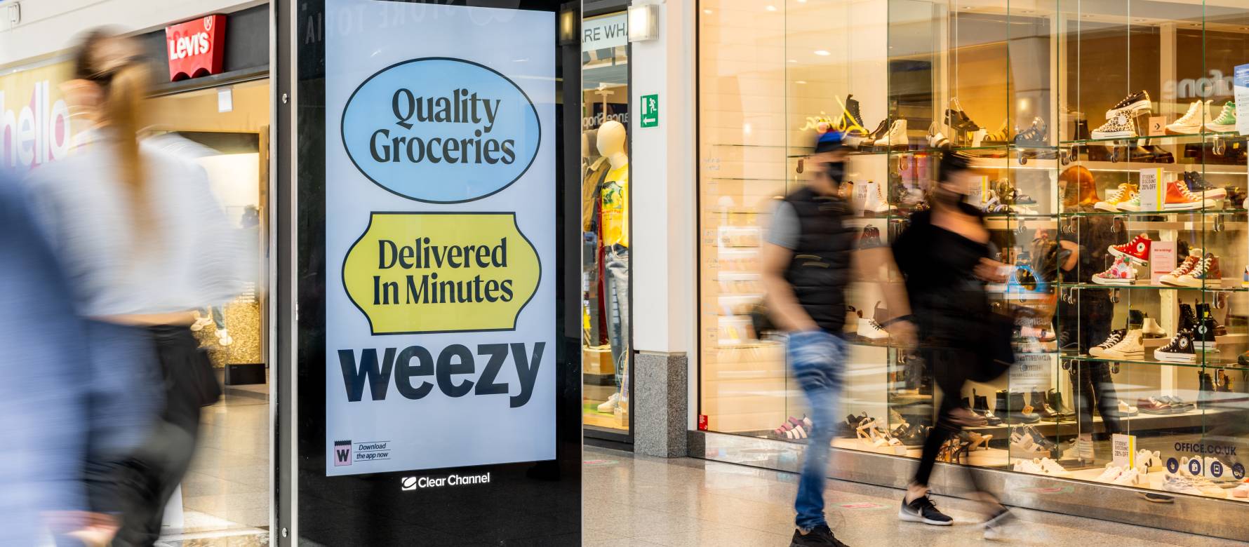 Digital screen in shopping mall showing advert for Weezy app.