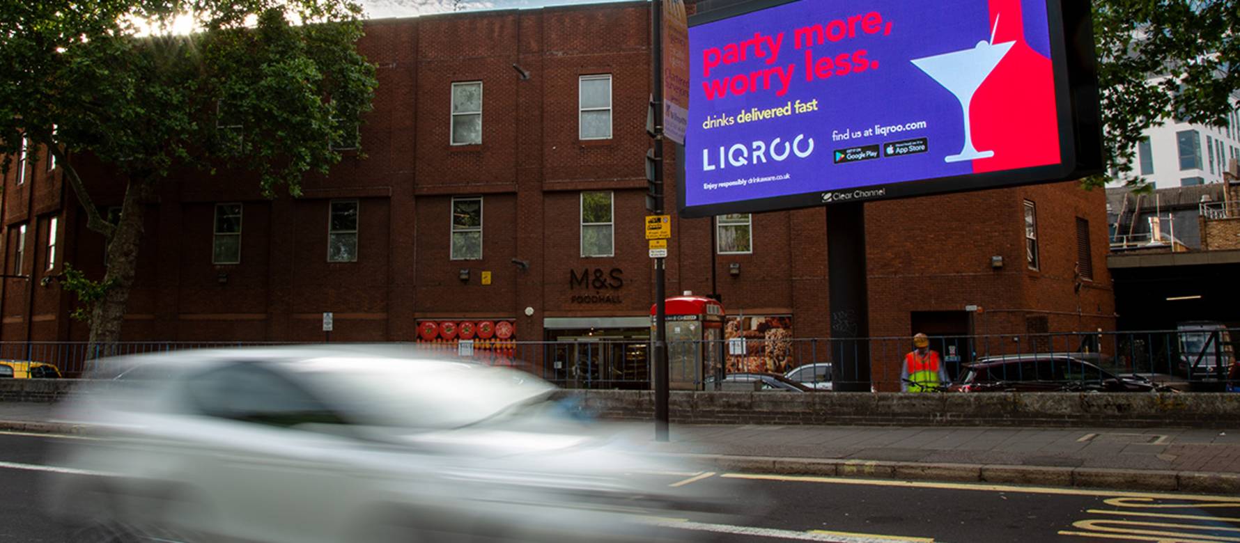 Billboard screen display 'party more, worry less' text over busy road