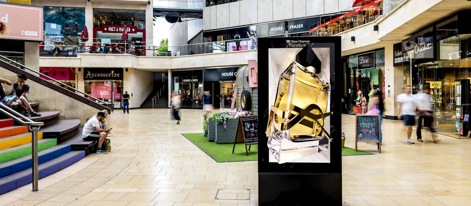 Shopping centre with an Adshel screen displaying a perfume bottle
