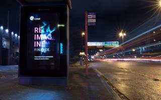 Digital screen on a bus stop showing CIMA ad