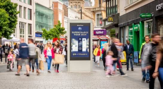 An Adshel Live advertising screen on a busy high street with a Nivea ad