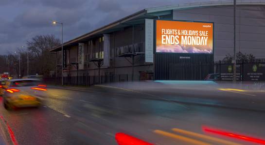 An easyJet ad on a digital roadside billboard at nighttime