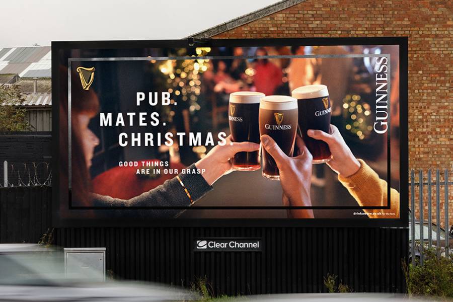 Guinness advertisement on a Clear Channel billboard by a busy road