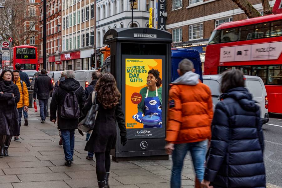 Compass advertisement on the side of a New World Payphone on a busy street in central London