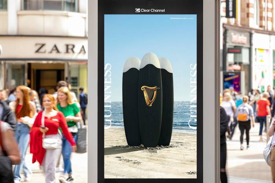A Guinness ad on an Adshel Live screen on a busy high street in the summer