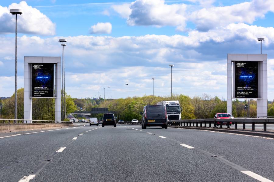 Storm screens on a busy road showing ads for KCAWLONDON