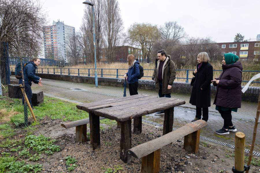 Five people sitting on a bench next to a newly planted tree funded by Clear Channel's re-greening and rejuvenation project