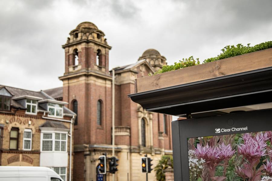 Corner of Clear Channel 'Living Roof' bus shelter, round roofed building in background