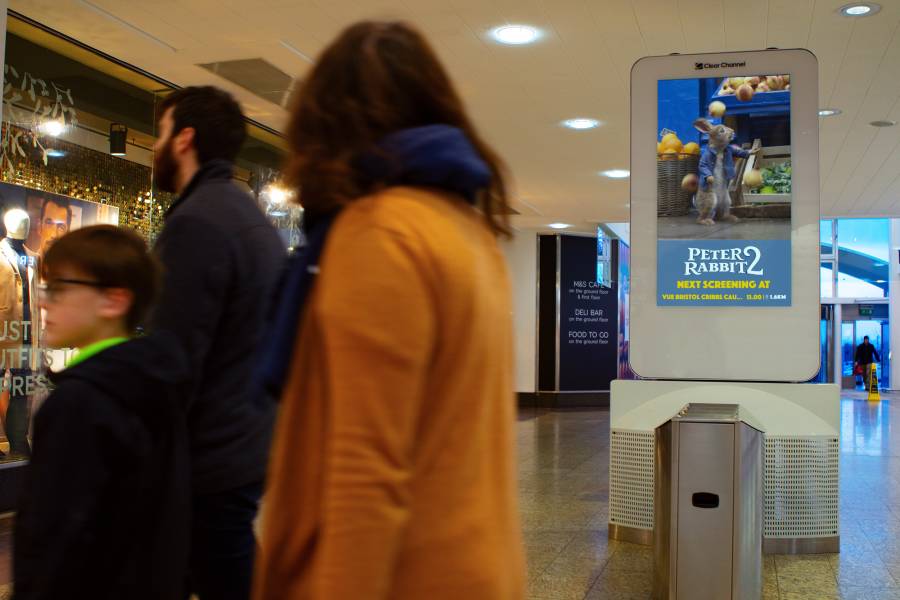 Digital screen in a busy shopping mall showing Peter Rabbit 2 ad