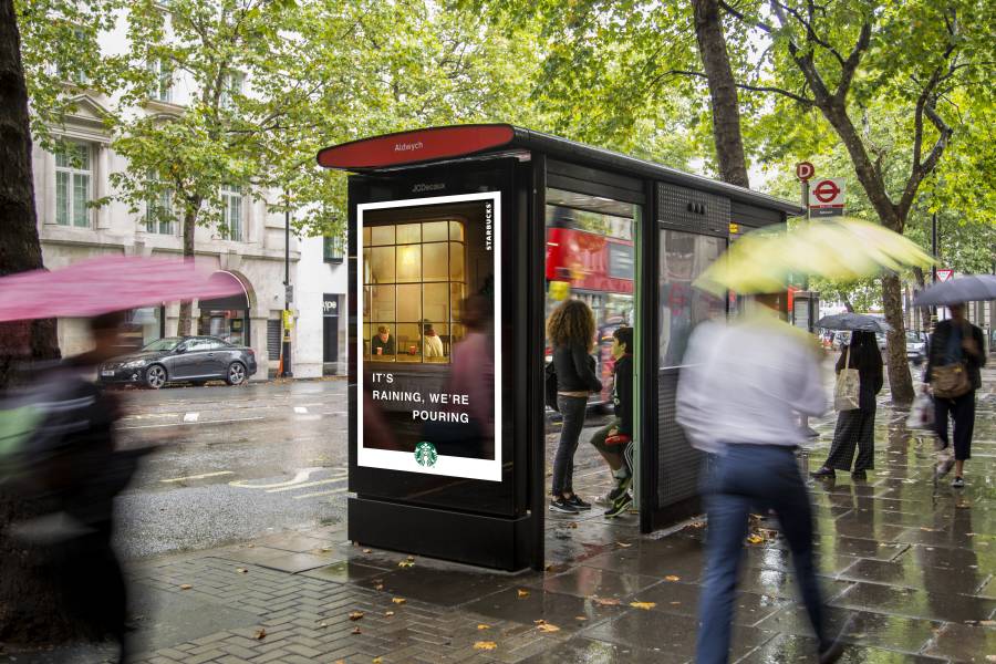 An Adshel screen on side of bus shelter displays Starbucks coffee in rainy day