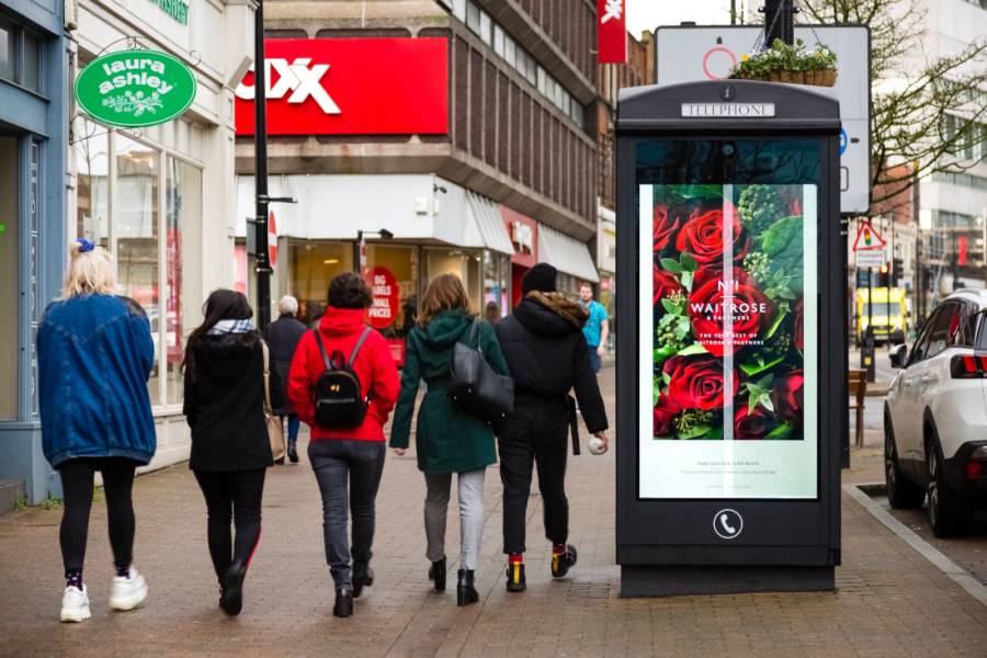 Valentines digital poster of red roses on a high street phonebox with three women walking past