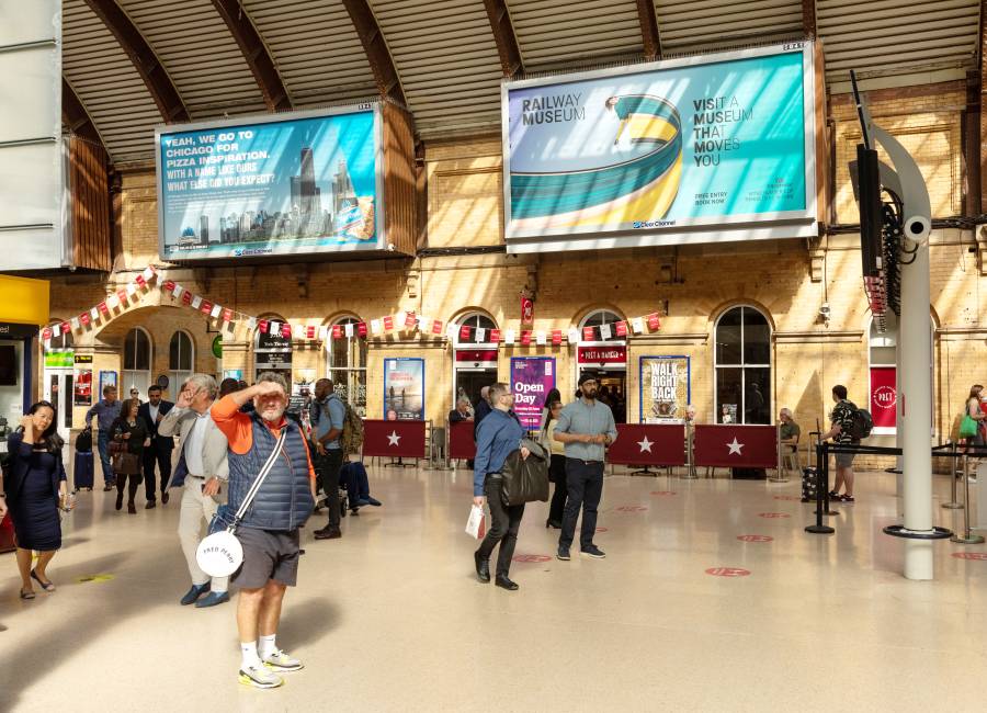 Rail station concourse with two Clear Channel billboards showing ads for Railway Museum & Chicago Town pizza