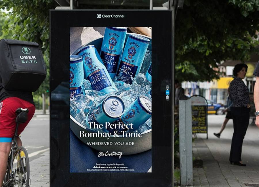 Gin and tonic pre-mixed drink advert on a digital bus shelter in summer with a cyclist passing by