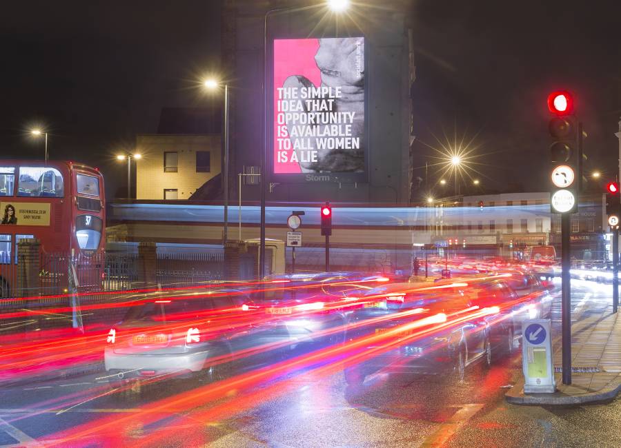 Storm billboard showcasing artist, Martin Firrell's, artwork above a busy junction at night in Peckham