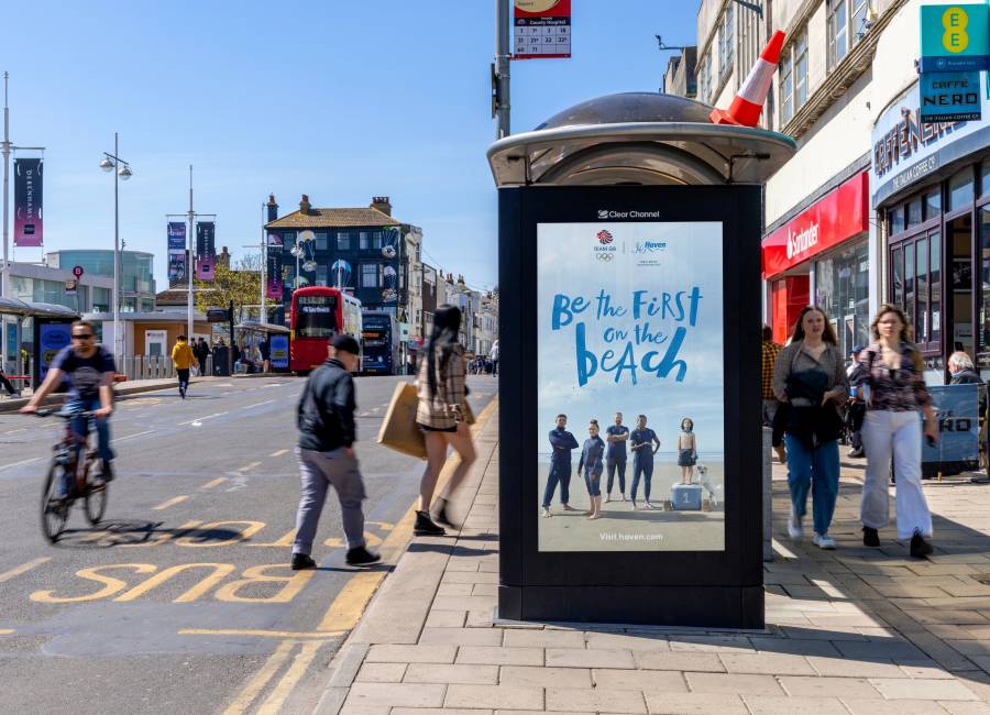 Digital bus shelter screen on a sunny day, featuring a Haven advert