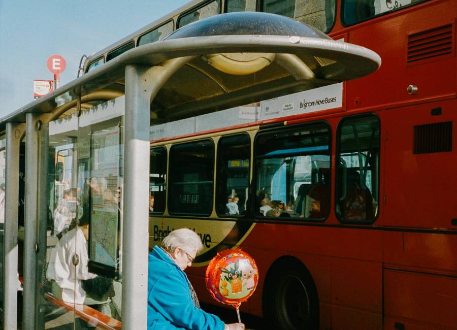 Woman waits in front of bus at bus stop with a balloon