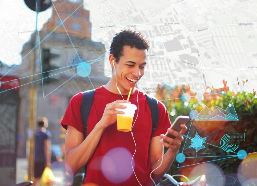 Young person holding a soft drink & wearing earphones.