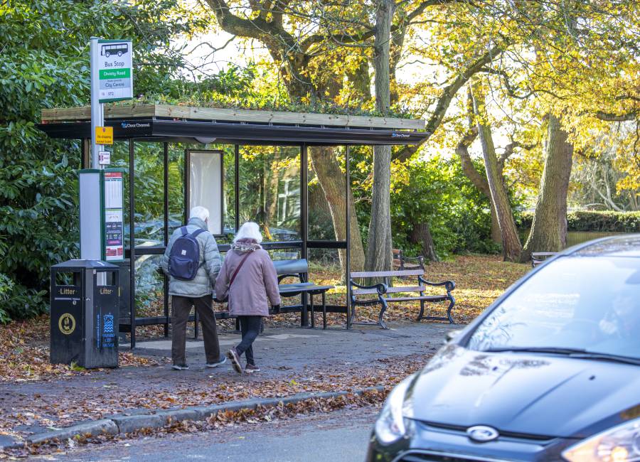 An image of a living roof bus shelter with people walking past.