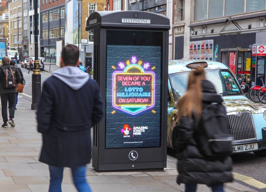 Digital phone box screen outside showing National lottery ad