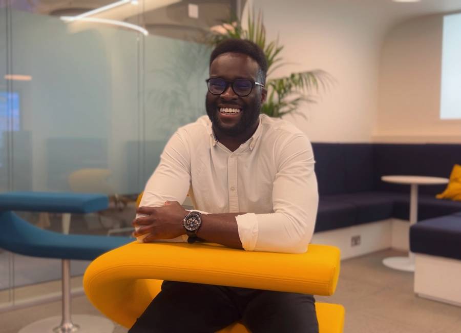 Chi Okorie, Junior Financial Account at Clear Channel, sitting on a yellow chair