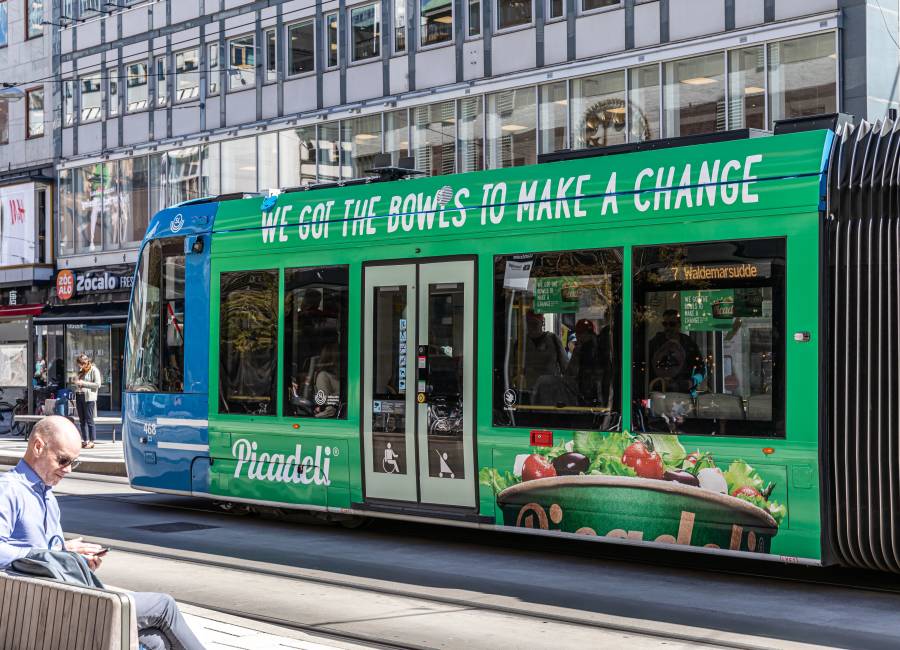 A green Picadeli advert on the side of a moving tram