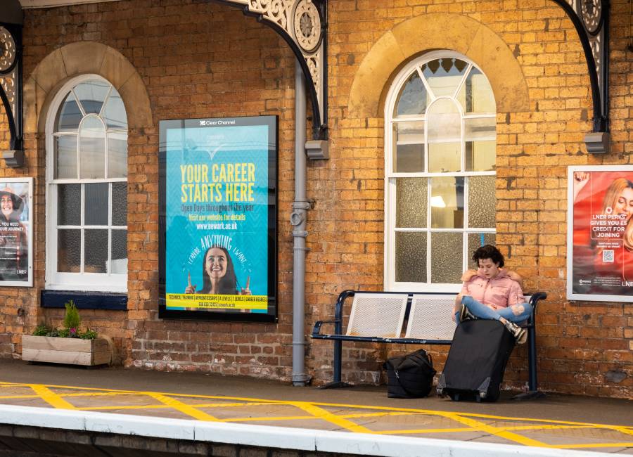 Rail platform showing with Clear Channel billboard showing ad for Newarc university
