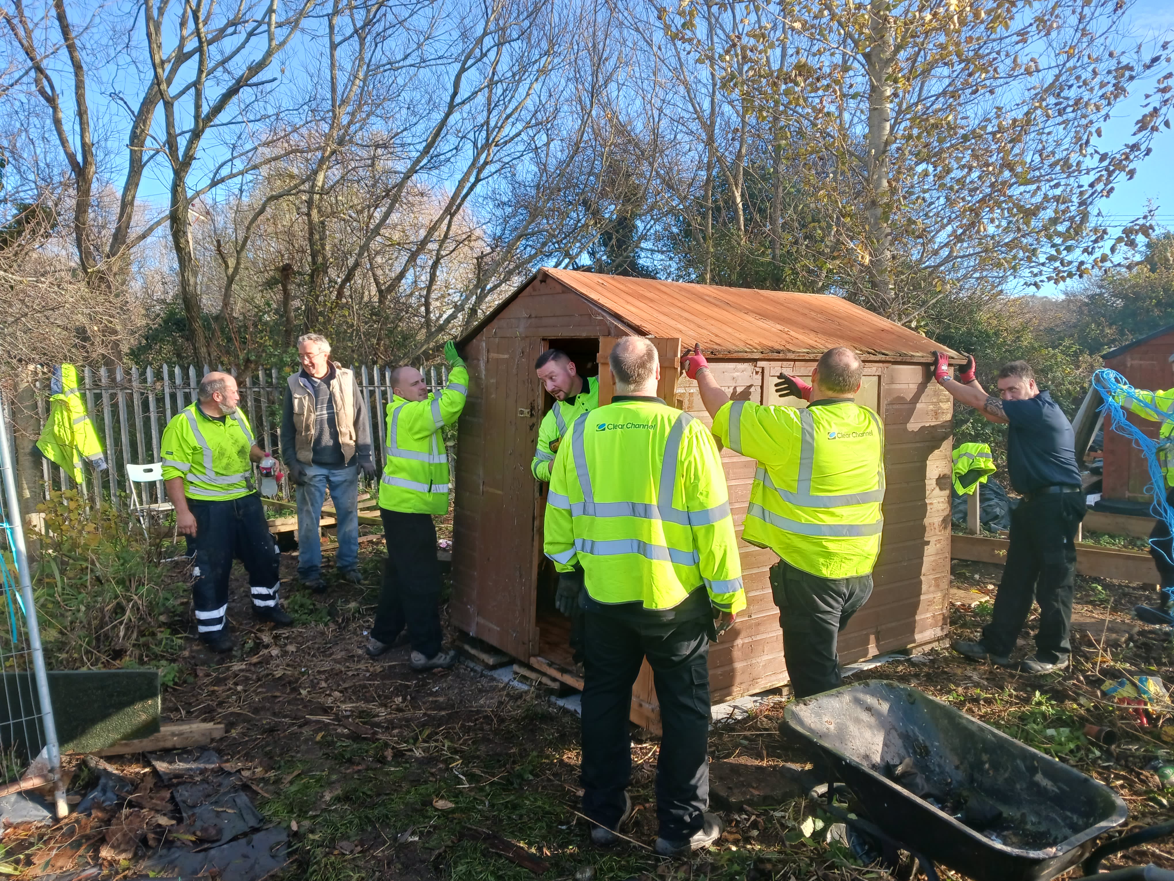 A group of men in reflective vests standing outside and working on a shed.