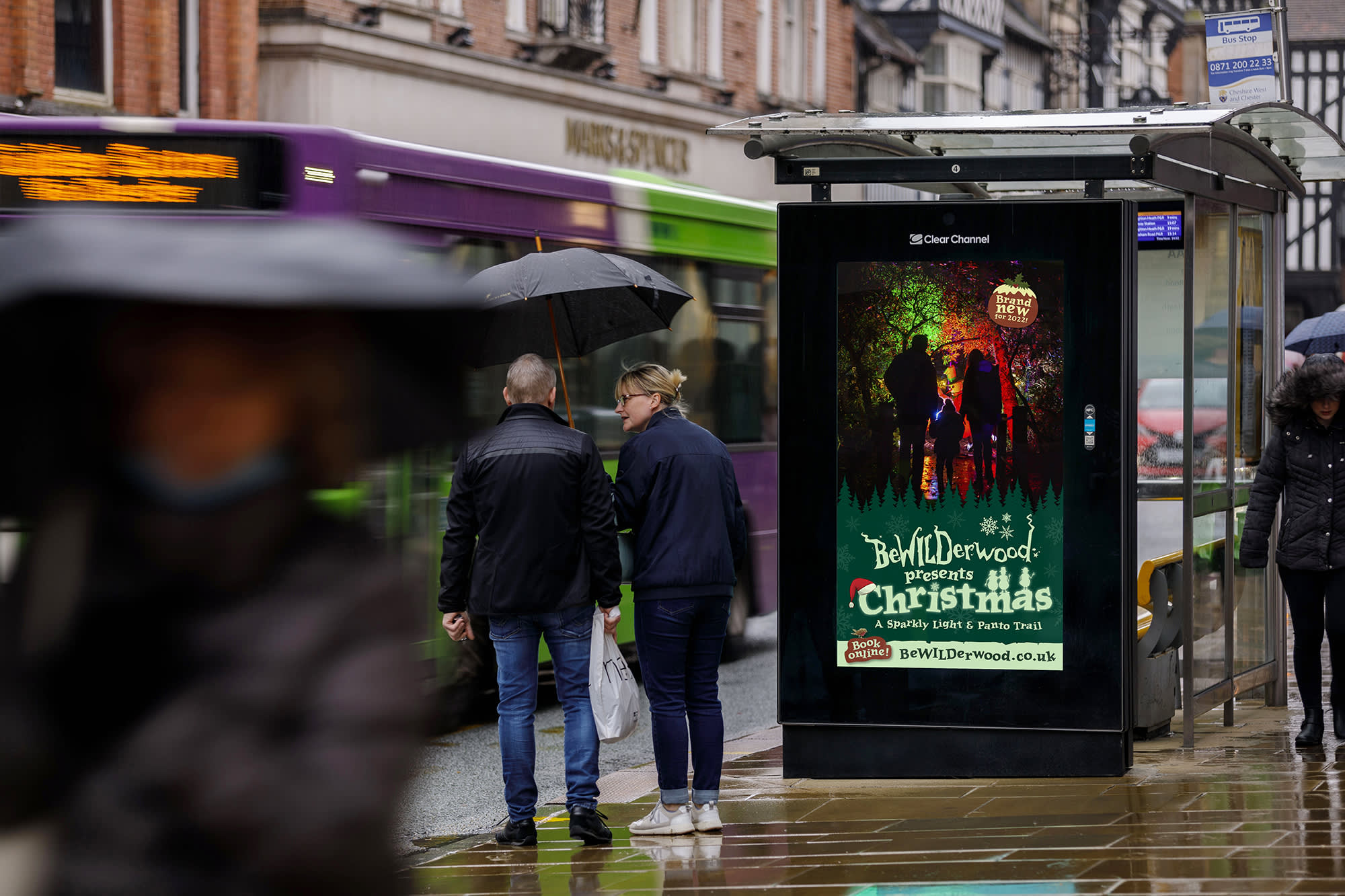 Digital screen on a bus stop opposite M&S showing ad for Bewilderwood presents Christmas