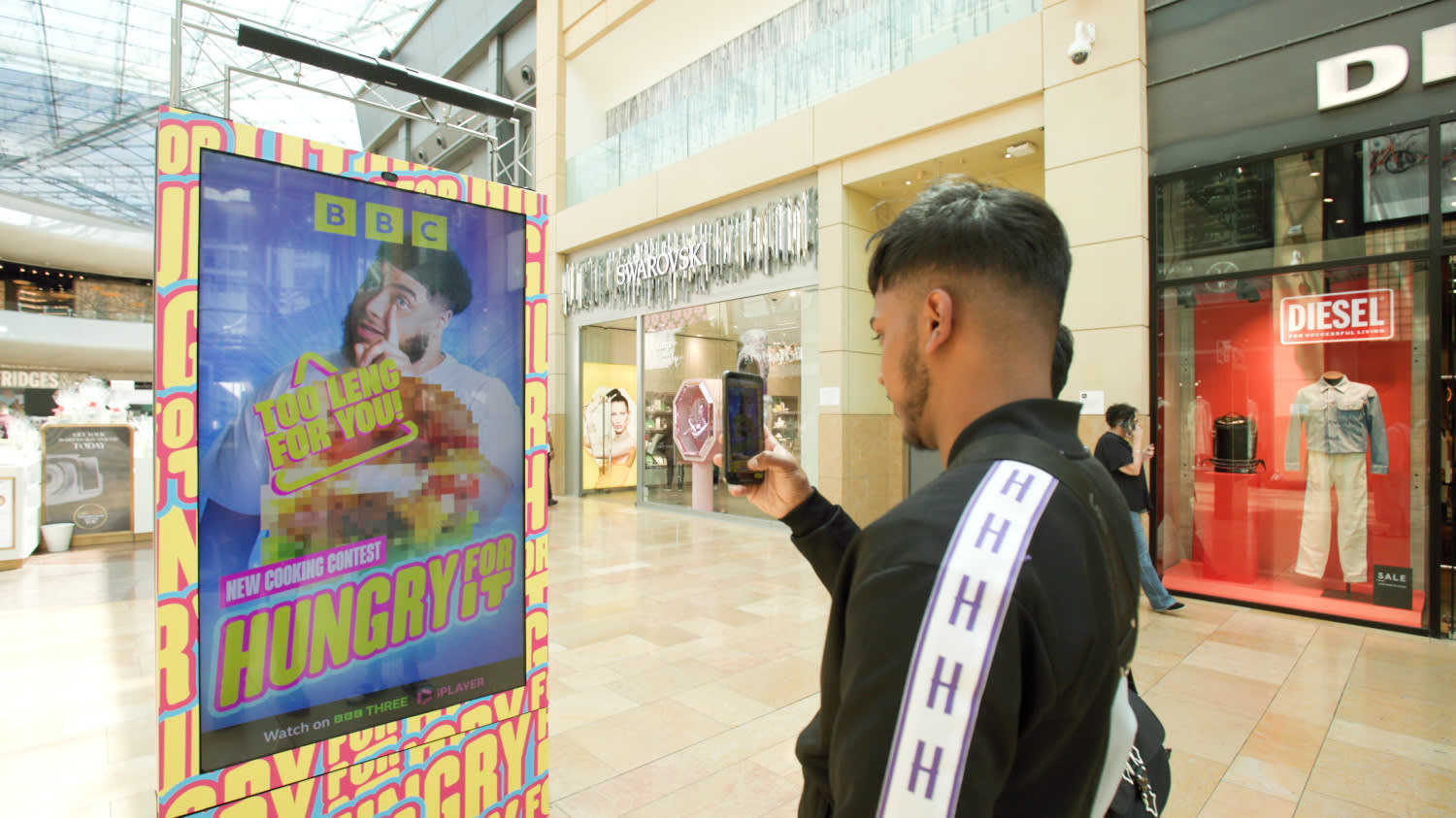 Digital screen in shopping mall showing ad for BBC show Hungry for it