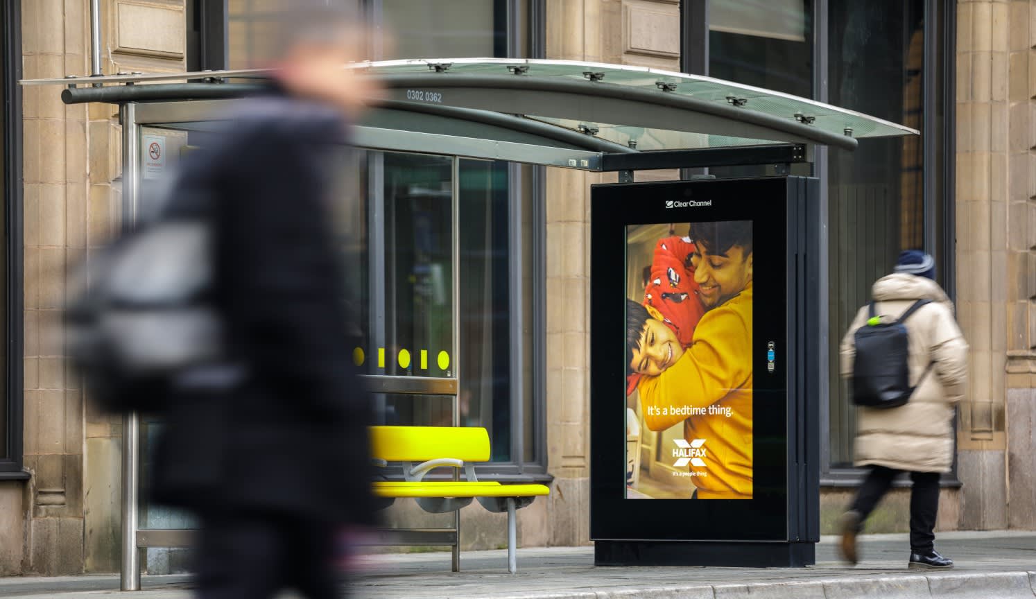 Halifax ad showing on a digital bus shelter screen with man walking past