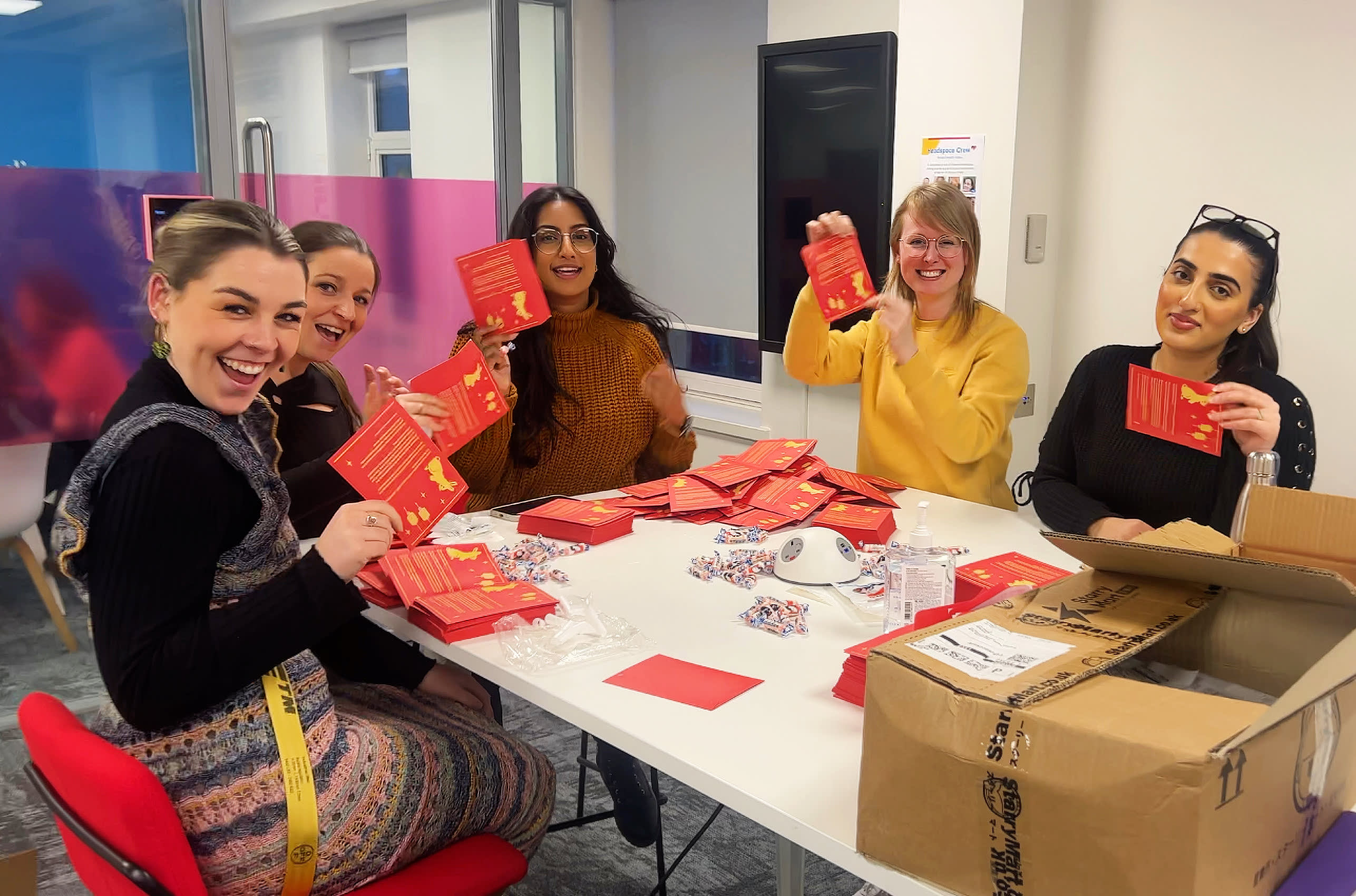 A group of women sitting at a table holding Chinese new year envelopes.