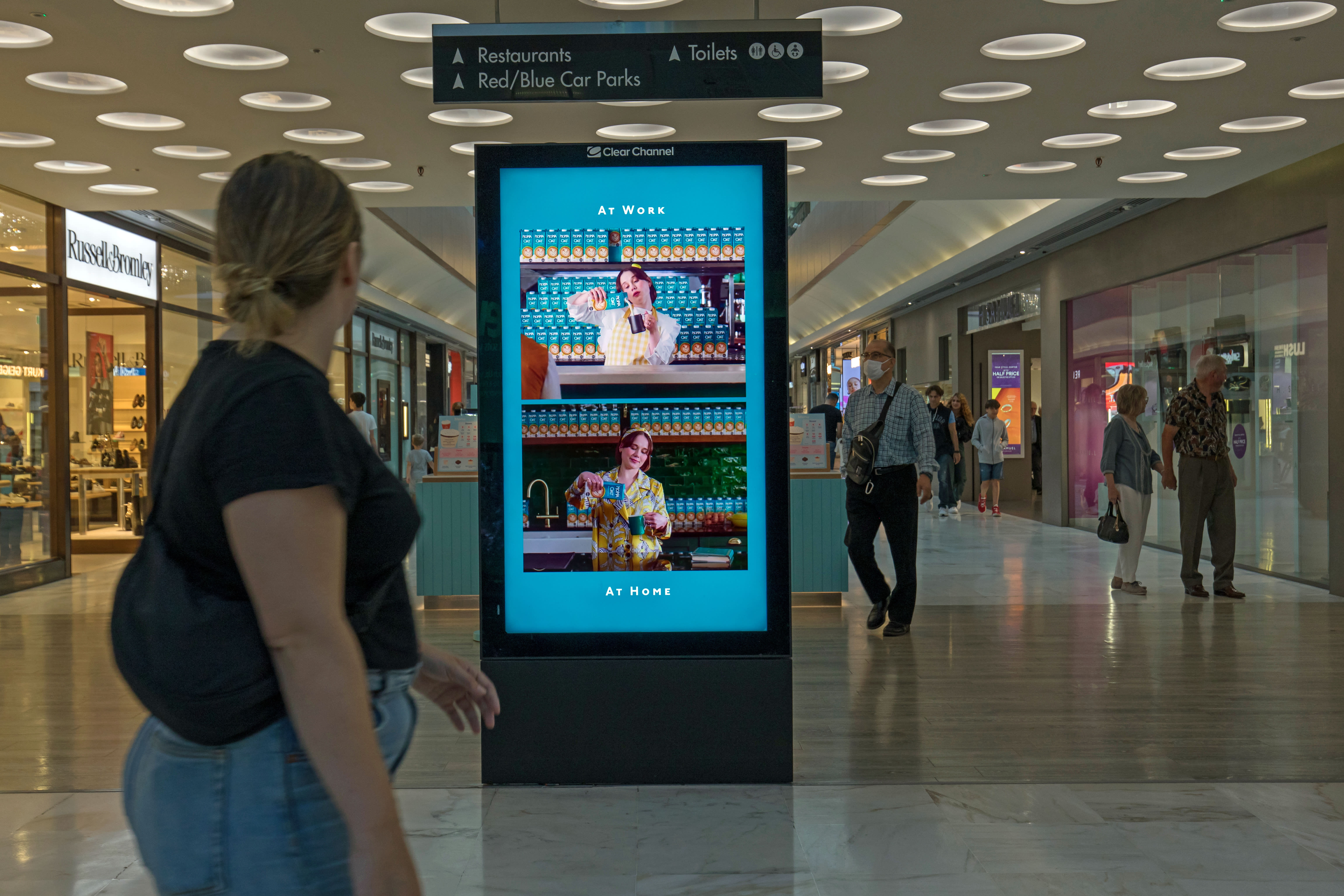 Digital screen in a busy shopping mall showing ad for Moma foods