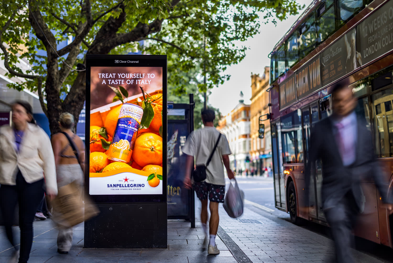 An Adshel Live screen displaying a Nestle campaign with a bus and people nearby