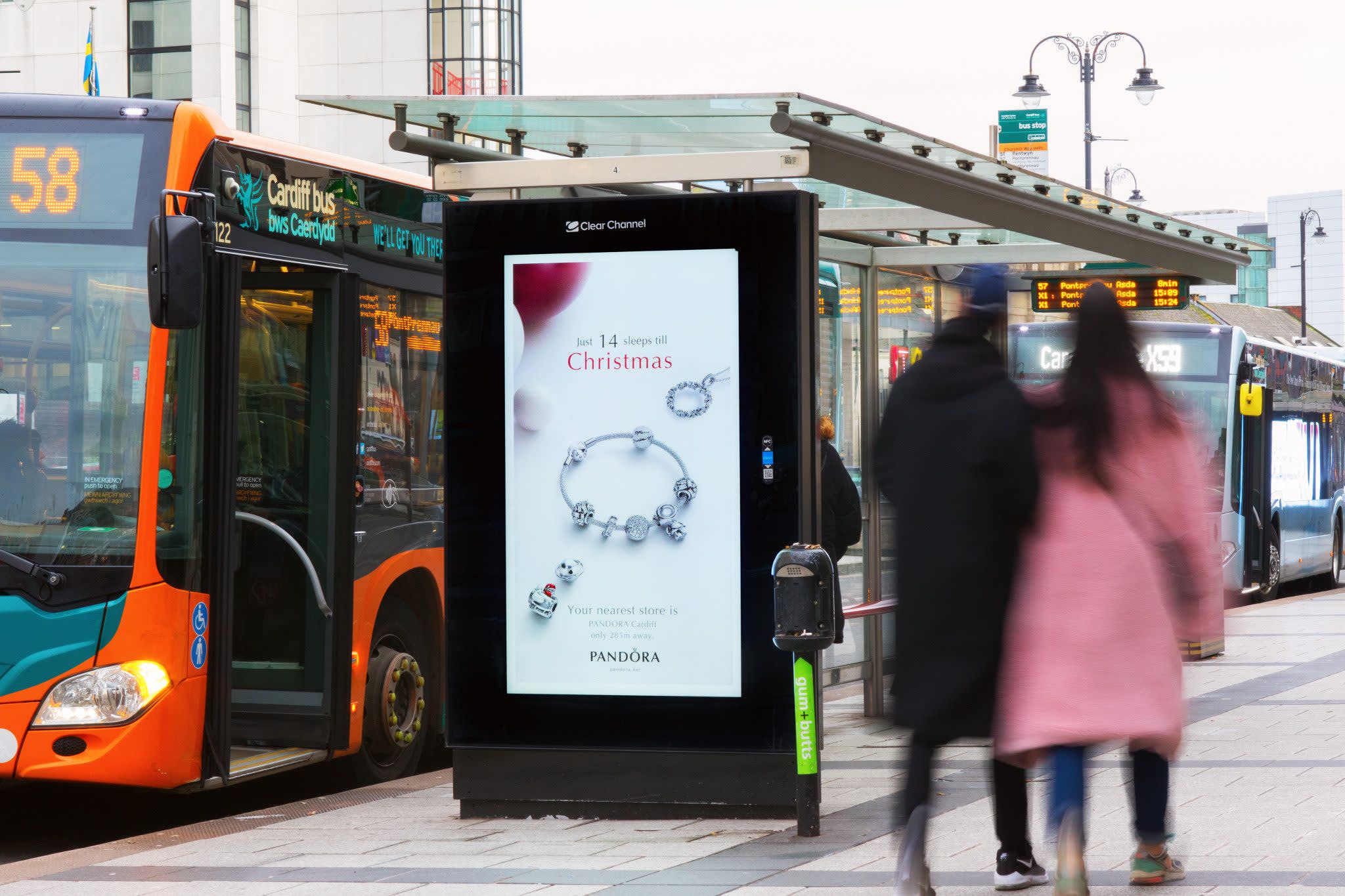 Digital screen on a bus stop showing ad for Pandora jewelry