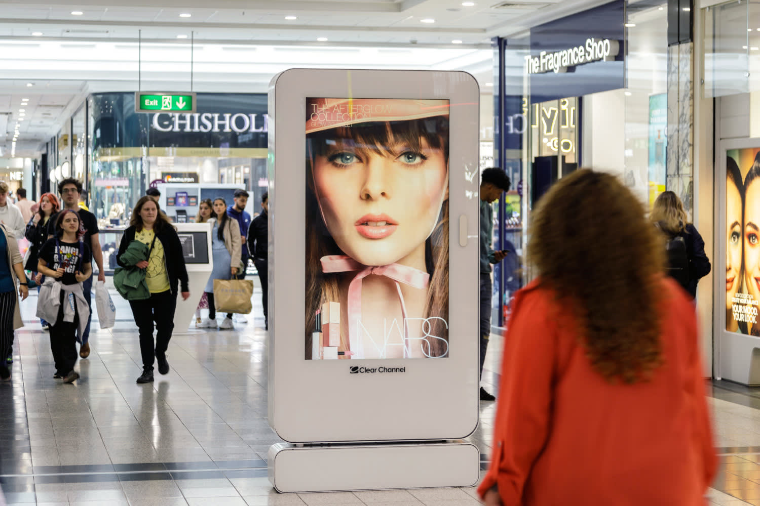 A Malls Live digital screen inside a shopping centre with shoppers walking around