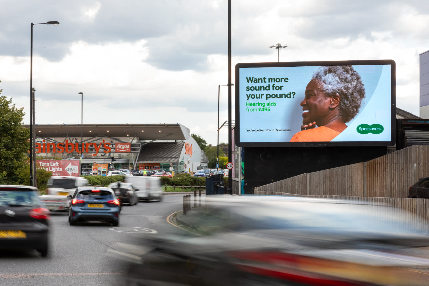Specsavers advert displaying on a Billboard Live screen next to a Sainsbury's supermarket